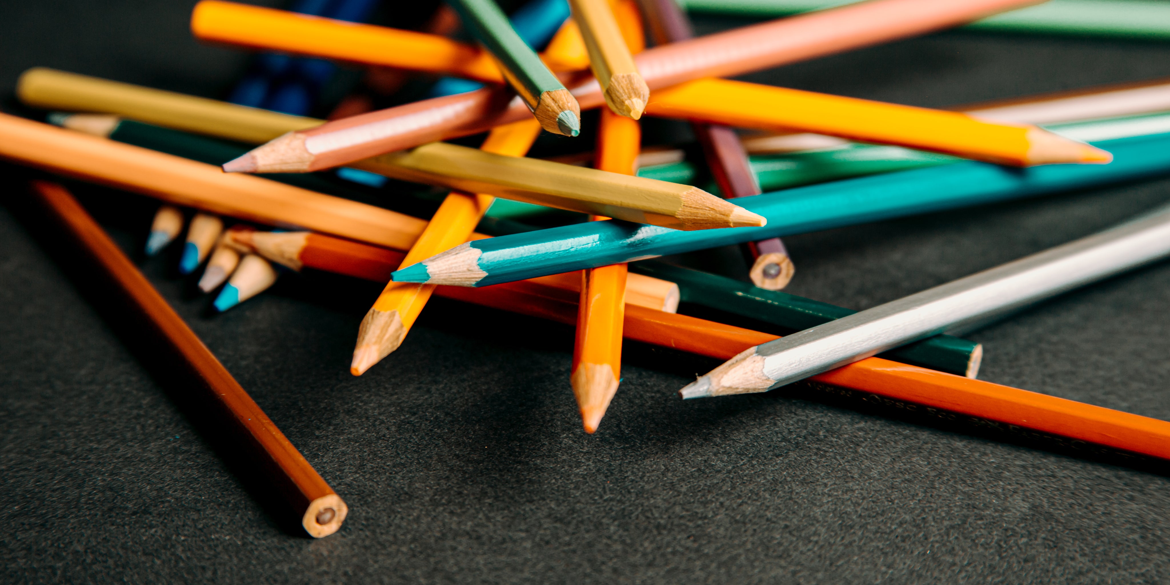 Colored pencils piled up on a black background