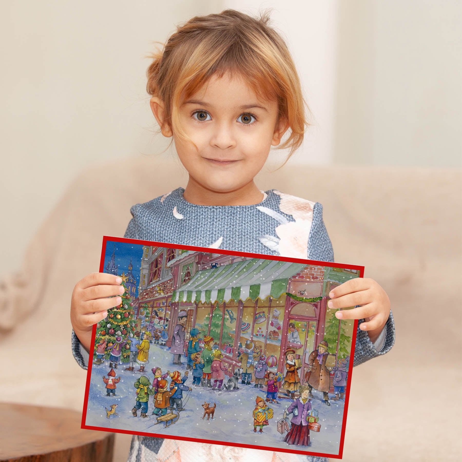 Mädchen mit Adventskalender "Am Spielzeugladen" in der Hand. thumbnail